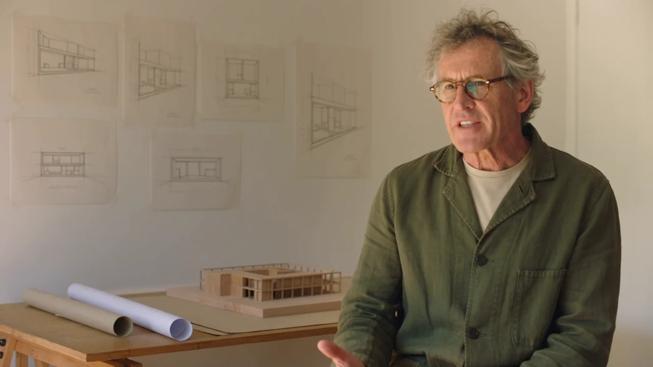 An architect talking in a warm, sunlit design studio.